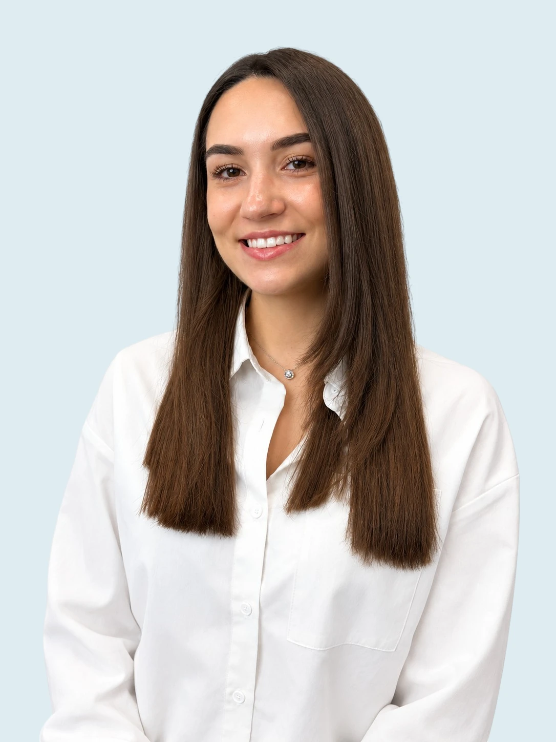 transparent Portrait of a smiling young woman with long brown hair wearing a white button-down shirt, against a pale blue background.